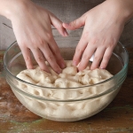 punching down bread dough in a bowl